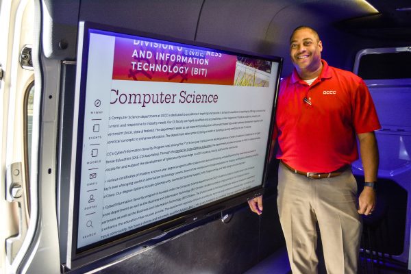 John Claybon standing next to the van monitor with a computer science display.