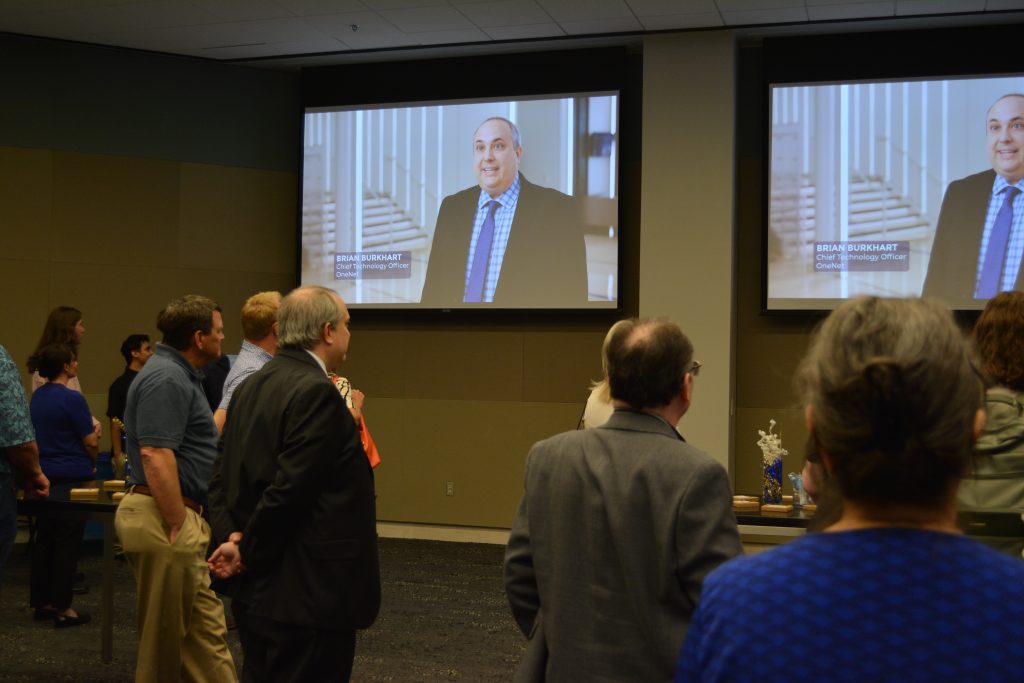 Rear view of guests watching anniversary video on big monitor